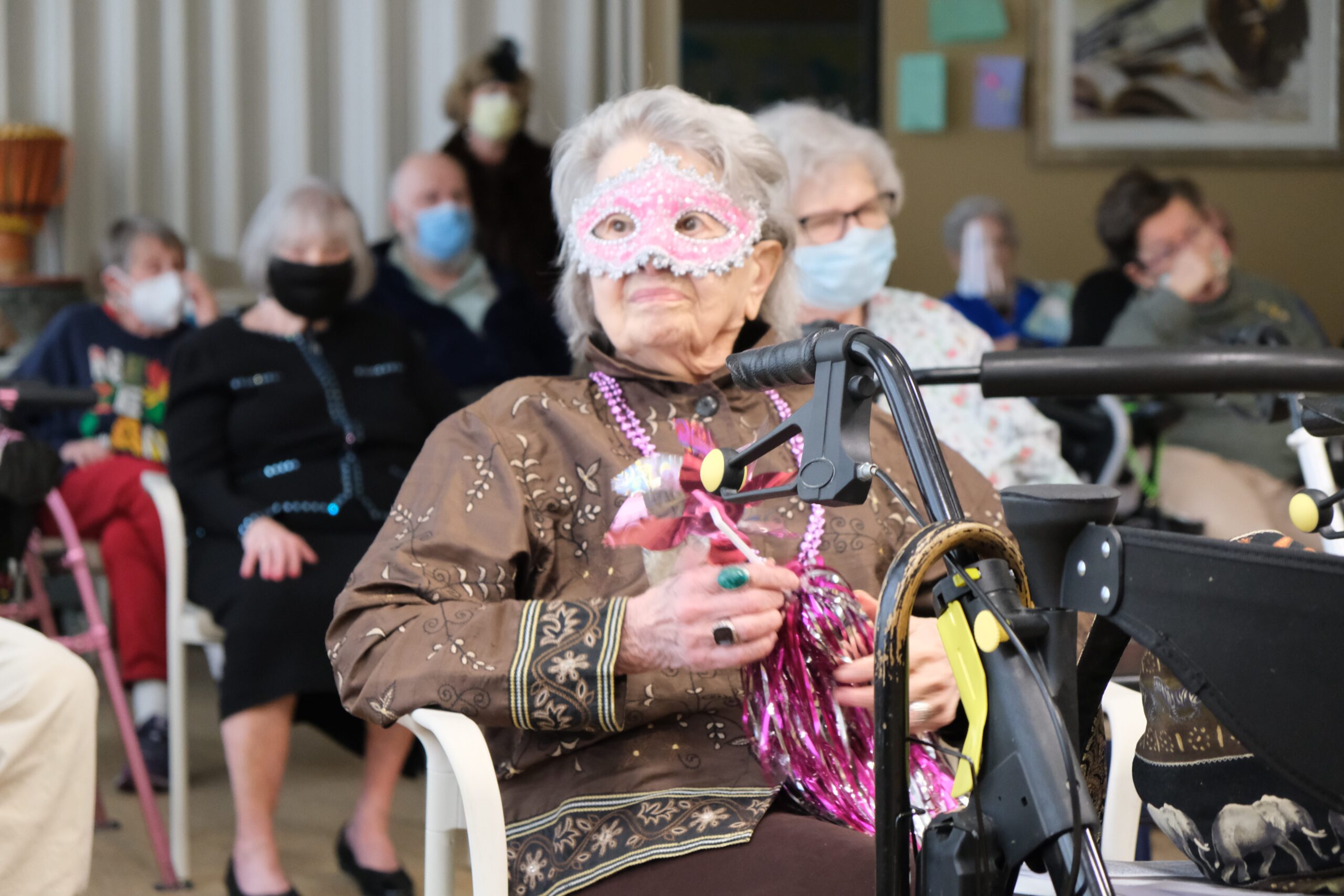 a resident in a masquerade mask surrounded by others for a party