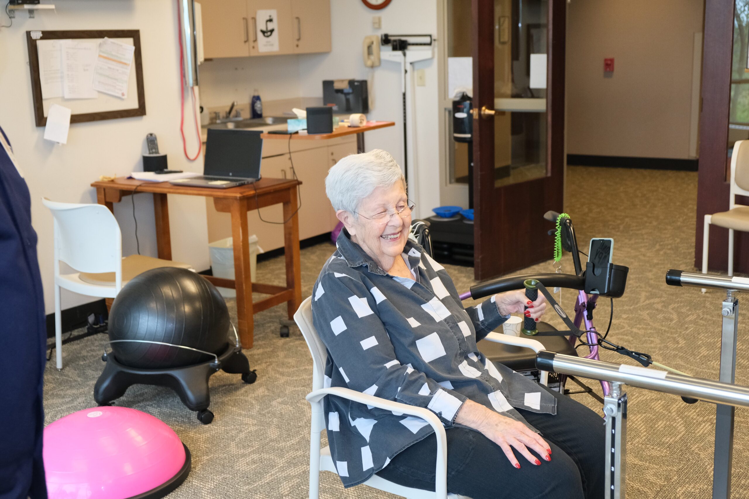 resident laughing while sitting in a therapy room surrounded by exercise equipment