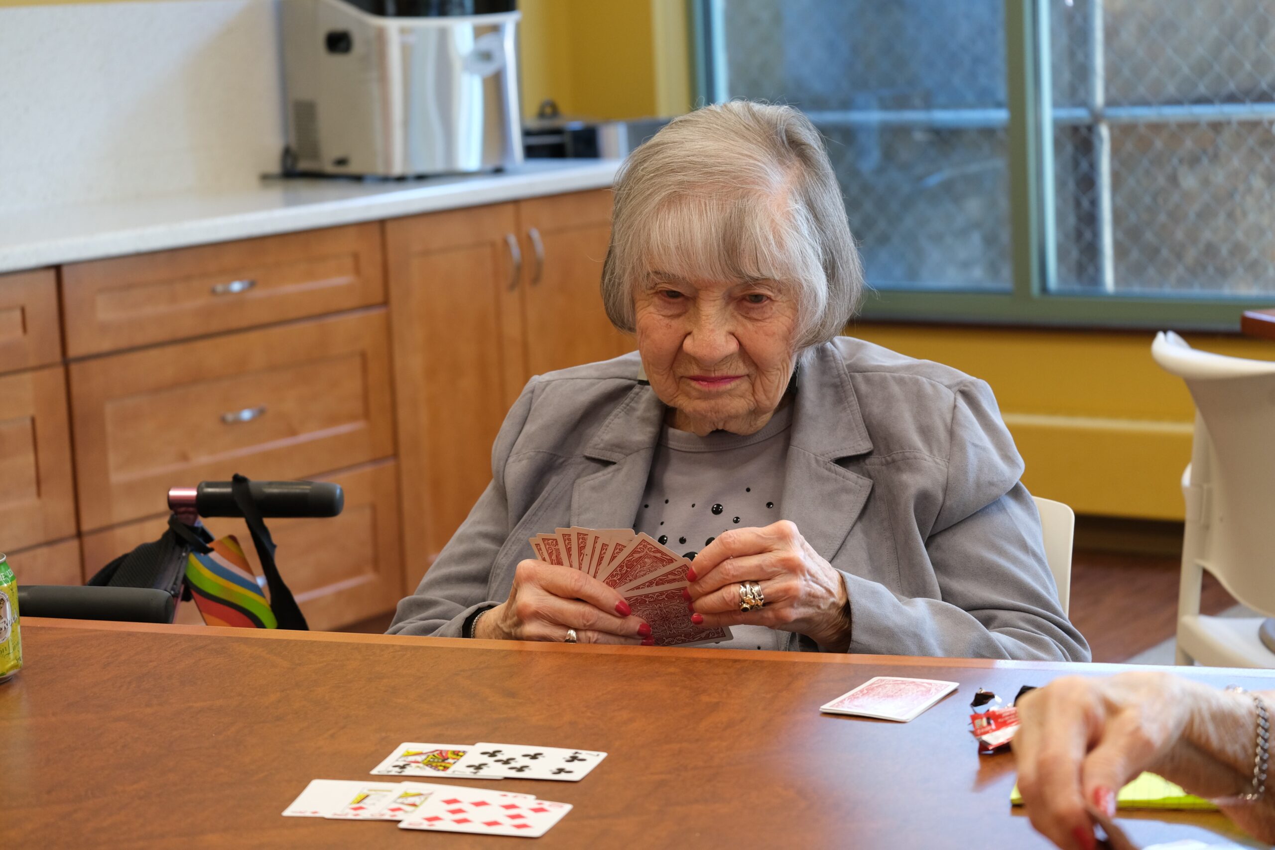 resident at a table with a deck of cards in her hands playing a game with another resident