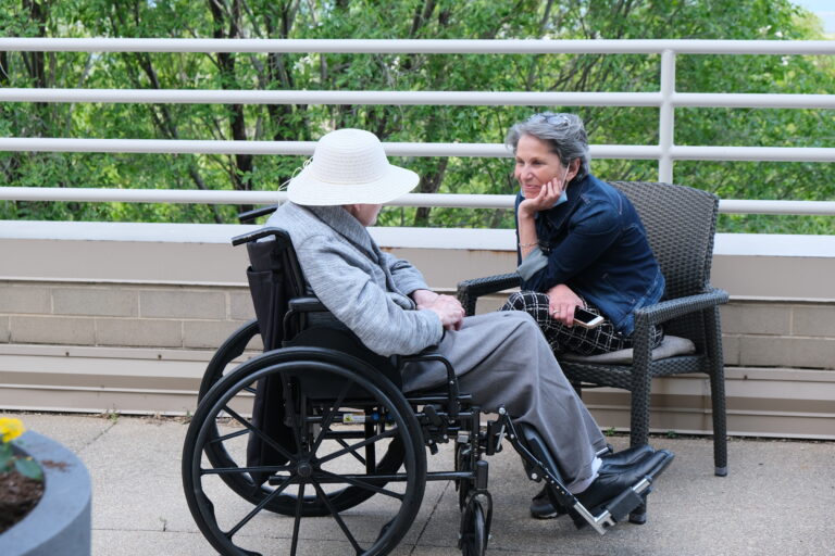 A staff member lovingly sits and listens to a resident outside