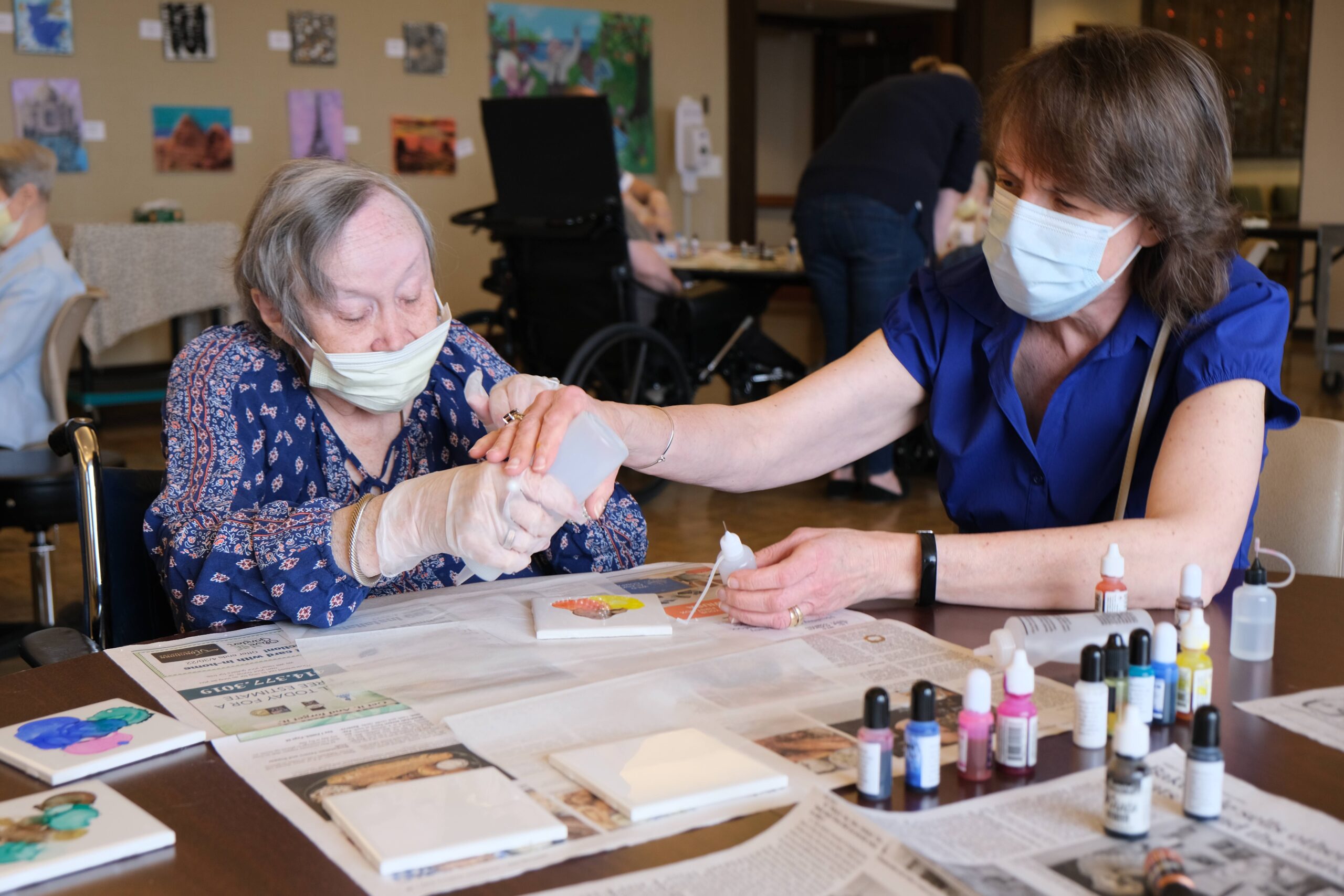 staff assisting a resident with making colorful art