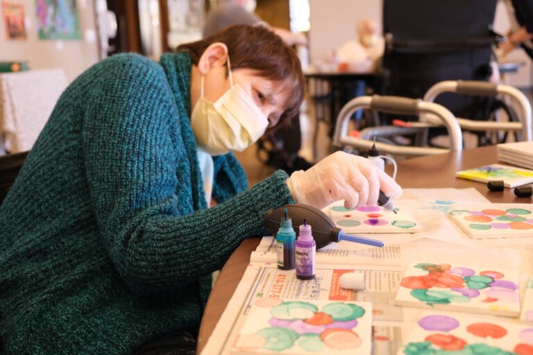 resident intently making colorful dotted art
