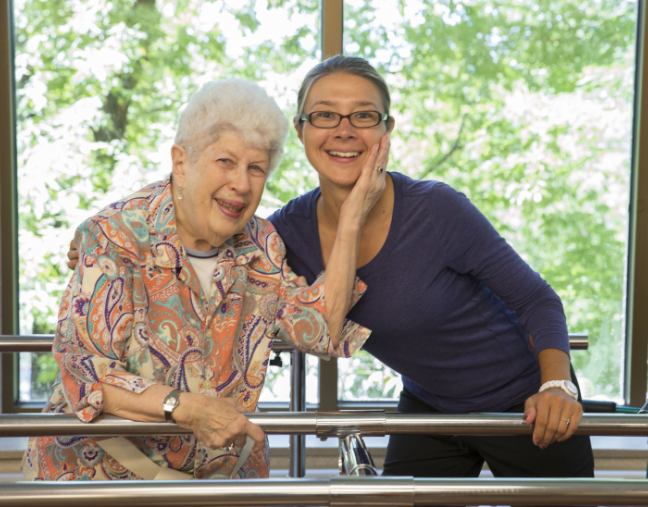 a resident and a staff member embracing and smiling while in a physical therapy room
