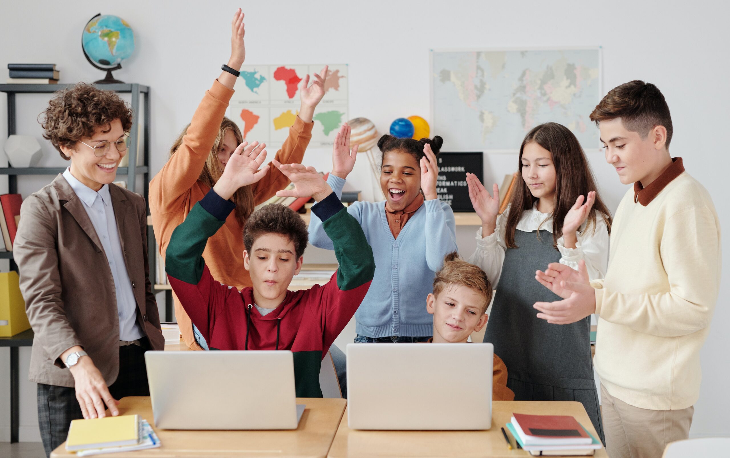 teens gathered around a computer looking excited with their hands in the air