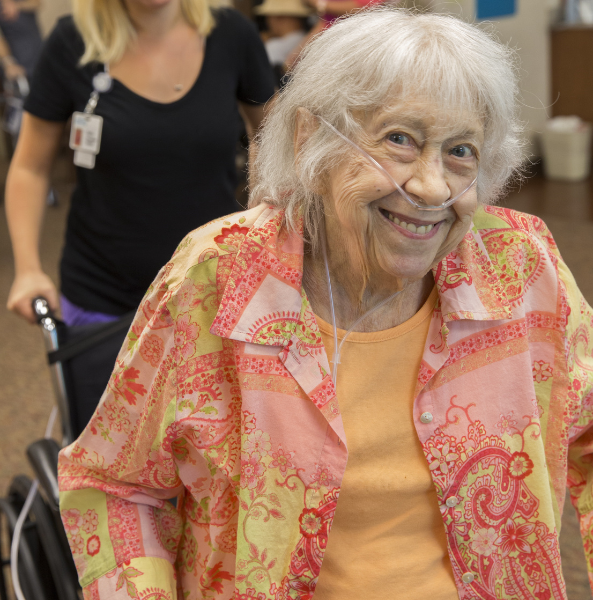 a vibrant resident smiling while being assisted in their wheelchair