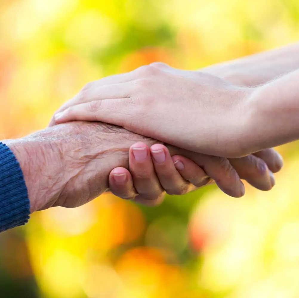 Caregiver cupping resident's hand
